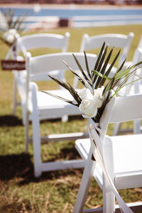 Close-up of white flower and palm leaf wedding decoration on white wooden chair