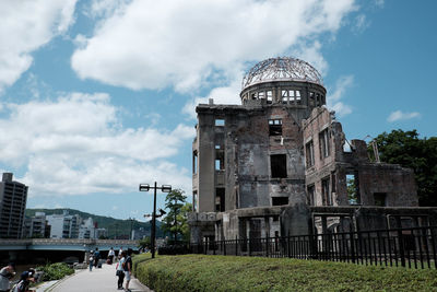 People in front of historical building against cloudy sky