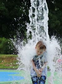 Full length of boy splashing water in swimming pool