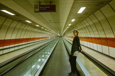 Side view of woman standing by railing on moving walkway