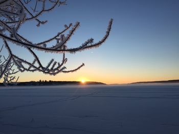 Snow covered landscape against sky during sunset