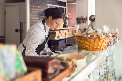 Female owner working at display cabinet in grocery store