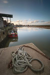 Rope and chain on pier by sea against sky