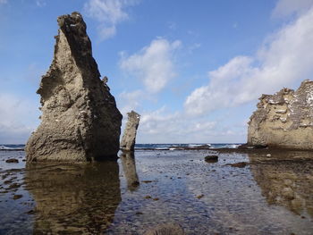 Rock formation on beach against sky