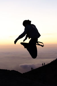 Silhouette man jumping against sky during sunset