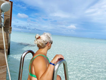 Rear view of woman in sea against sky