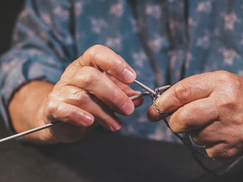 Midsection of person knitting while sitting at table