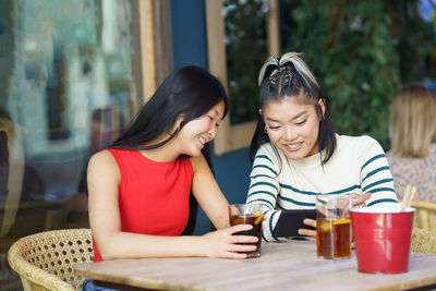 Portrait of smiling friends sitting on table