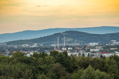 Trees and cityscape against sky during sunset