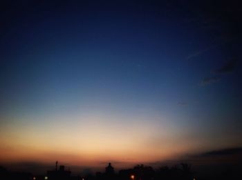 Silhouette trees against clear sky at night