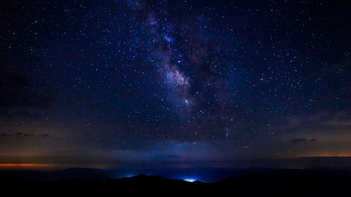 Silhouette mountain against star field at night