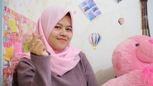 Portrait of young woman standing against pink wall