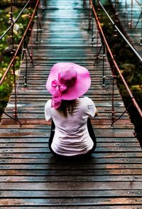 Rear view of girl sitting on pink wood