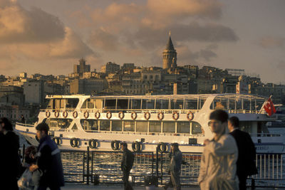 Rear view of people on river against buildings in city