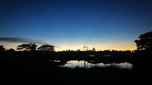 Silhouette trees on landscape against sky during sunset