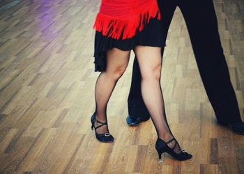 Low section of couple dancing on hardwood floor