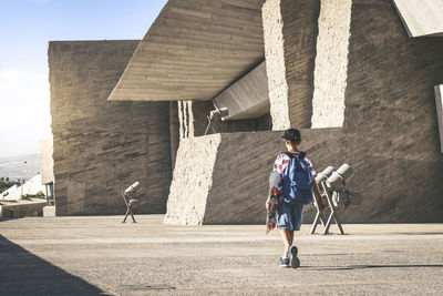 Full length rear view of boy walking on footpath