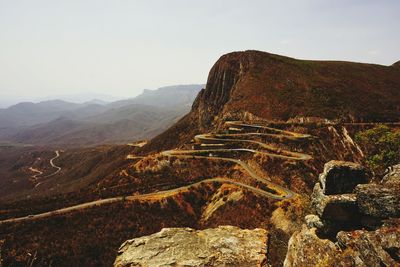High angle view of curved road along rocky mountains
