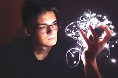 Close-up portrait of man holding christmas lights