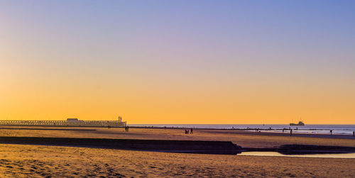 Scenic view of beach against clear sky during sunset