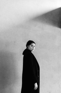 Young woman looking away against wall