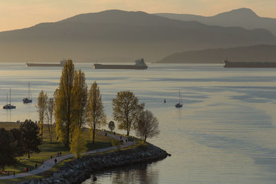 Scenic view of english bay by mountains during sunset