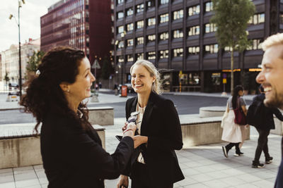 Female entrepreneur smiling with coworkers while standing outdoors