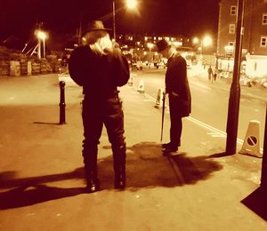 Rear view of woman standing on street at night