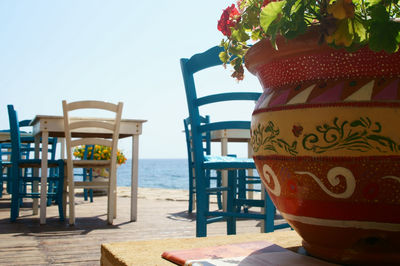 Close-up of chairs on beach against clear sky