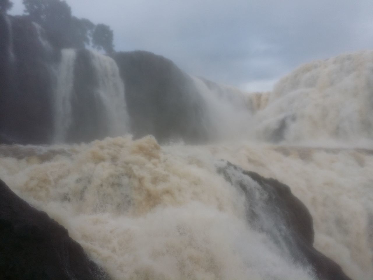 SCENIC VIEW OF WATERFALL IN MOUNTAINS