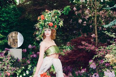 Portrait of young woman standing by flowering plants against trees