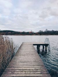 Wooden pier over lake against sky