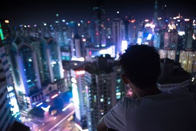 Rear view of man above illuminated city at night