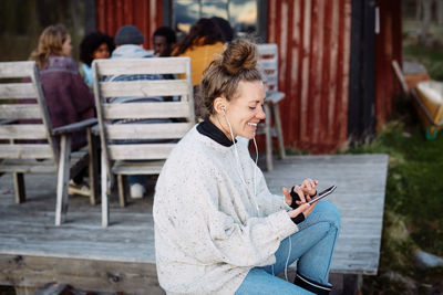 Side view of woman using phone while sitting on seat