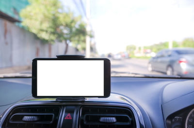 Close-up of smart phone with blank screen on car dashboard