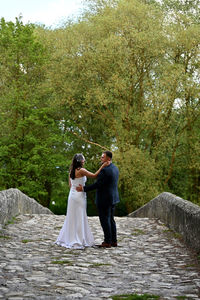 Friends standing on footpath amidst trees