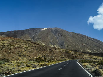 Road amidst mountains against blue sky