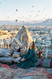 Rear view of woman looking at cityscape against sky