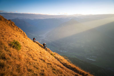 People riding bicycles on mountain against sky