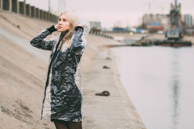 Young woman standing against sky in city