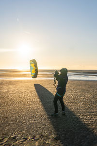 Woman kiteboarding at beach against clear sky