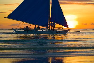 Sailboat in sea against sky during sunset