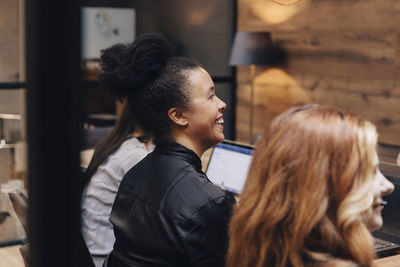 Happy businesswoman sitting amidst female colleagues in board room during meeting