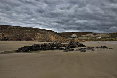 Scenic view of beach against cloudy sky