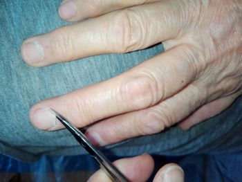 Midsection of man cutting fingernail skin