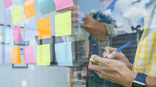 Midsection of business colleagues seen through window working in office