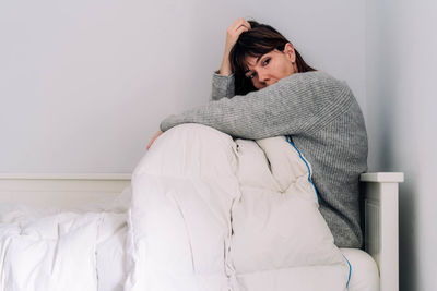 Young woman sitting on bed at home