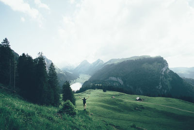 Rear view of man standing on cliff against mountains