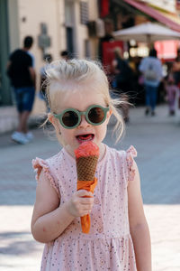 Little girl eating ice cream. cool green glasses