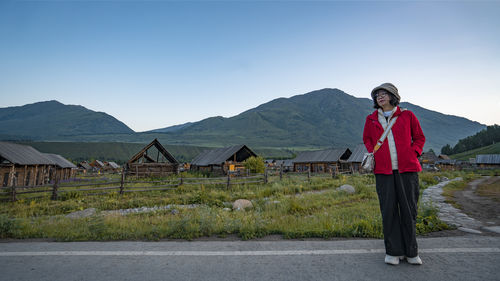 Rear view of man standing on road against clear sky